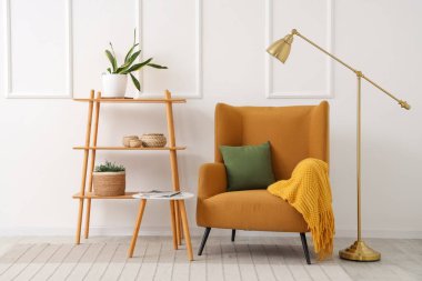 Brown armchair, coffee table and shelving unit near white wall