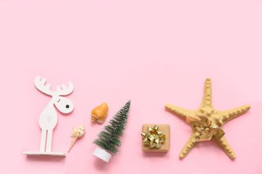 Deniz yıldızı, deniz kabuğu ve pembe arka planda Noel süsü. Üst görünüm