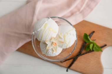 Çiçekli, naneli ve beyaz ahşap masaya yapışmış vanilyalı dondurma topları.