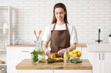 Mutfakta naneli su hazırlamak için limon kesen genç ve güzel bir kadın.