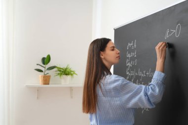 Sınıfta yazı tahtasının yanında genç bayan matematik öğretmeni.