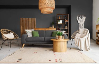 Hasır sepetli ahşap masa ve şık oturma odasının içinde saksı çiçekleri.