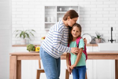 Anne ve kızı okuldan önce mutfakta sarılıyorlar.