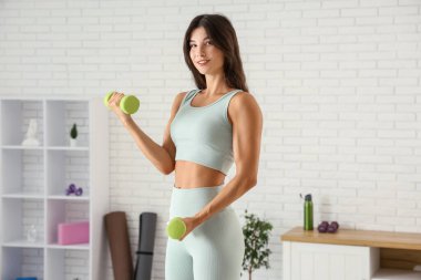 Spor salonunda eğitim dumbbells ile genç kadın