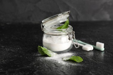 Bir kavanoz diş pudrası ve siyah arka planda yapraklar ve fırçalar. Yakın çekim.