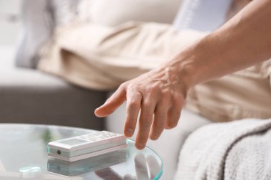 Erkek el evdeki klimayı uzaktan kumandayla kapatıyor.