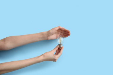 Mavi arka planda yuvarlak ampullü kadın elleri