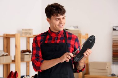 Erkek ayakkabıcı tamirhanede ayakkabı insole kesiyor.