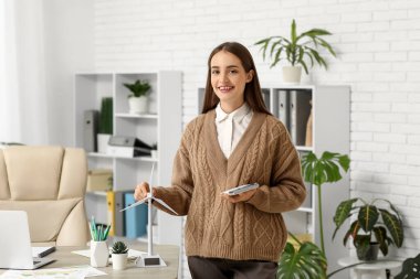 Ofisteki masasında hesap makinesi ve rüzgar türbini modeli olan kadın mühendis