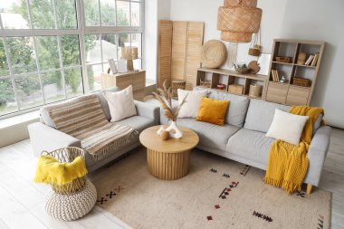 Gri kanepeleri ve pencerenin yanındaki kahve masası olan aydınlık oturma odasının içinde.