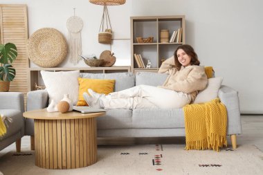 Gri kanepede uzanmış güzel bir genç kadın.