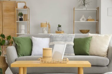 Gri kanepeli, kahve masalı ve çiçekli aydınlık oturma odasının içi.