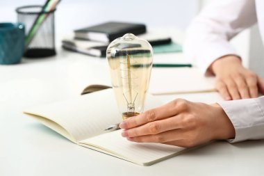 Ofisteki masada ampulü ve defteri olan iş kadını, yakın plan.