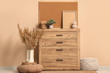 Çekmeceler, otlar, puf ve çerçeveler bej duvarın yanında.