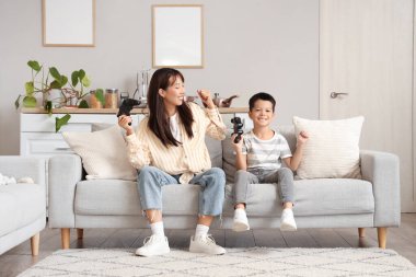 Genç anne ve küçük oğlu evde video oyunu oynuyorlar.