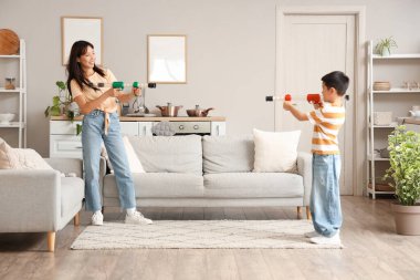 Genç anne ve küçük oğlu evde oyuncak silahlarla oynuyorlar.