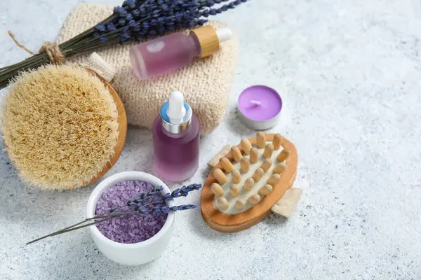 Hafif arka planda lavanta yağı şişeleri ve masaj vücut fırçalarıyla güzel bir kompozisyon, yakın plan.