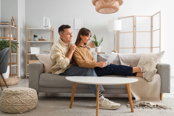 Young couple with laptop watching movie on sofa at home