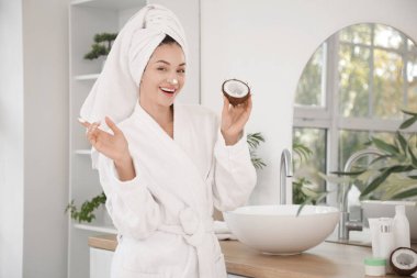 Banyoda aynanın yanında hindistan cevizi kremalı güzel genç bir kadın.