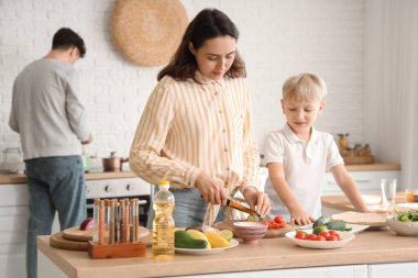 Annesi mutfakta Fajita için domates kesen sevimli bir çocuk.