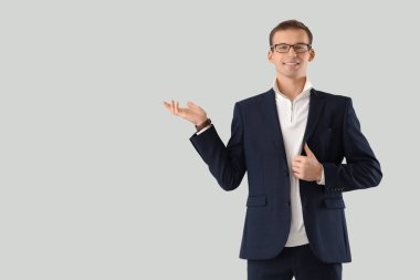 Gözlüklü genç işadamı arka planda bir şey gösteriyor.