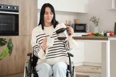 Tekerlekli sandalyedeki güzel kadın evde kahve yapıyor.
