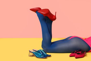 Renkli arka planda uzanan şık ayakkabılı kadın