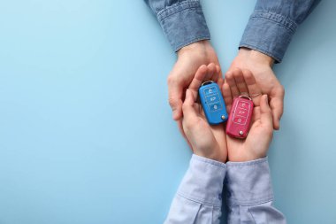 Mavi arka planda araba anahtarı olan çift, üst görünümde.