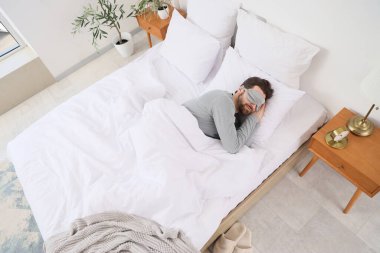 Maskeli yakışıklı bir adamın yatak odasında uyuduğu bir sabah.