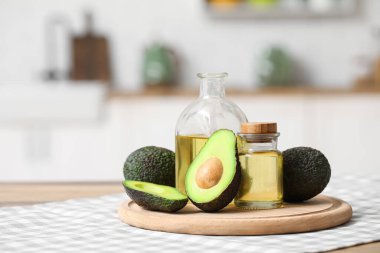 Şişeler dolusu taze yağ ve mutfak masasının üzerinde avokado olan kesme tahtası.