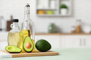Şişeler dolusu taze yağ ve mutfak masasının üzerinde avokadolar olan kesme tahtası.