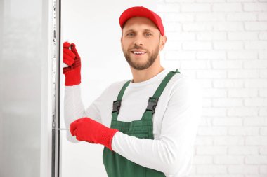 Odadaki pencereyi tamir eden tornavidalı bir erkek işçi.