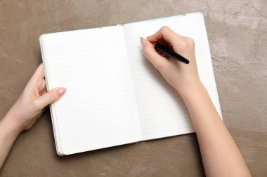 Kahverengi zemin üzerinde defter ve kalem olan eller