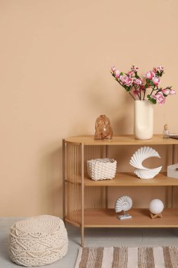 Oturma odasındaki yumuşak pouf 'un yanındaki konsol masasında çiçek açan vazo.