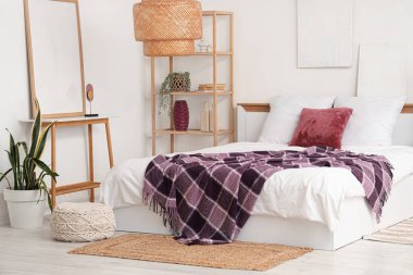 Yatağında raf ünitesi, ev bitkileri ve mor battaniye olan modern yatak odası.