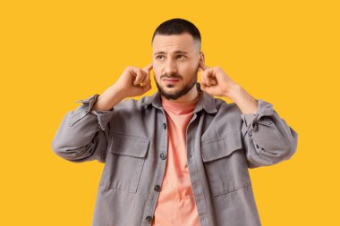 Genç adam sarı arka planda gürültüden muzdarip.