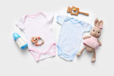 Bebek kıyafetleri, oyuncaklar ve hafif arka planda bir şişe sütle kompozisyon