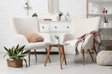 Oturma odasının içinde koltuklar, masa ve yeşil bitkiler