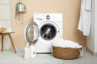 Modern çamaşır makinesi, hasır sepeti ve deterjan şişeleriyle şık bir çamaşır odası.