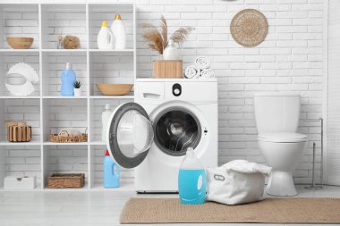 Modern çamaşır makinesi, raf ünitesi, klozet ve deterjan şişeleriyle şık bir çamaşır odası.