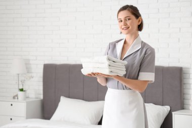 Otel odasında temiz havluları olan genç oda hizmetçisi.