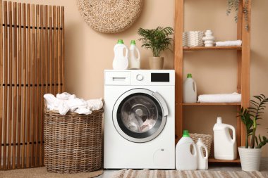 Modern çamaşır makinesi, hasır sepeti ve deterjan şişeleriyle şık bir çamaşır odası.