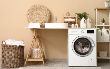 Modern çamaşır makinesi, lavabo ve deterjan şişeleriyle şık bir çamaşır odası.