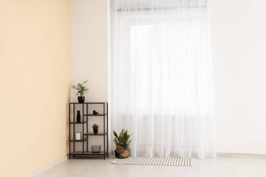 Odada ışık perdesine yakın bitkileri olan raf ünitesi.