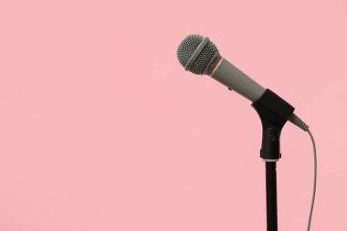 Profesyonel mikrofonla kayıt stüdyosundaki pembe duvarın yanında durun.