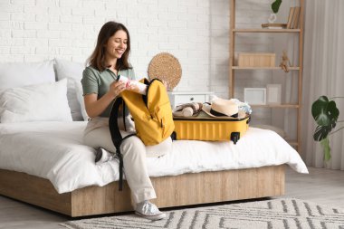 Sırt çantasını haritayla birlikte açık otel odasında açan güzel genç bir kadın.