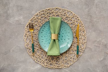 Gri arkaplanda altın çatal bıçak seti olan güzel bir masa.