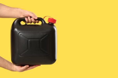 Sarı arka planda erkek eller teneke kutuyu tutuyor.