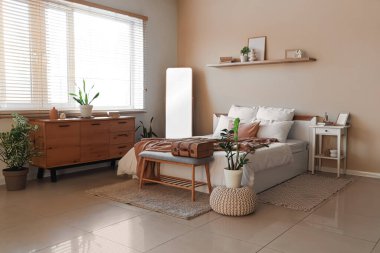 Büyük aynalı, yumuşak banklı ve raflı rahat bir yatak odası.