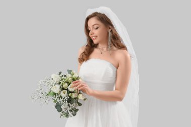 Beyaz gelinlik içinde, açık arkaplanda çiçekler olan güzel bir gelin.